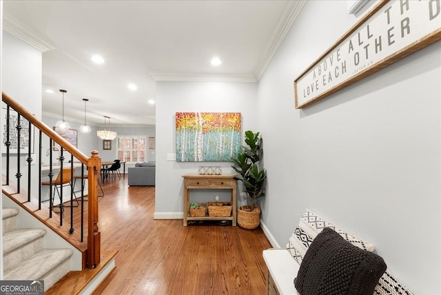 corridor with hardwood / wood-style flooring, crown molding, and a notable chandelier