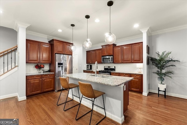 kitchen with a kitchen breakfast bar, sink, hardwood / wood-style flooring, an island with sink, and stainless steel appliances