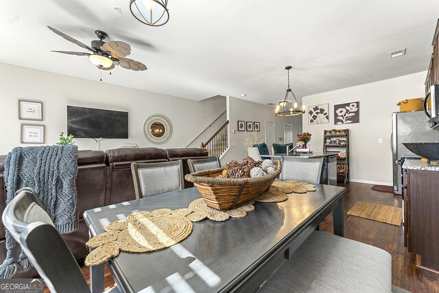 dining area with ceiling fan with notable chandelier and dark hardwood / wood-style floors