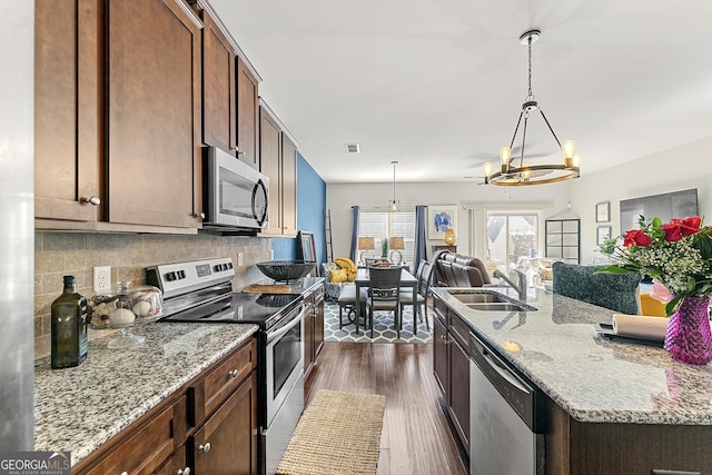 kitchen featuring sink, hanging light fixtures, stainless steel appliances, dark hardwood / wood-style floors, and a chandelier