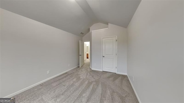 unfurnished bedroom featuring light colored carpet and lofted ceiling