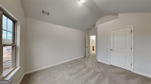 unfurnished bedroom featuring light colored carpet and lofted ceiling