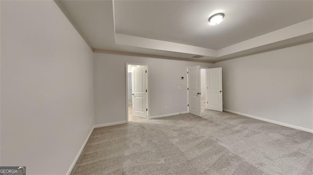 unfurnished bedroom with a tray ceiling and light carpet