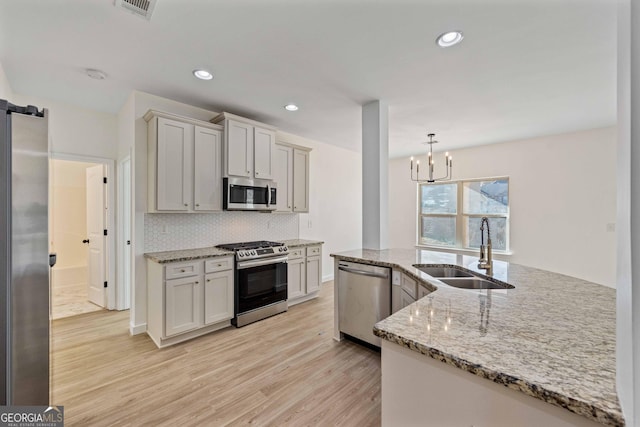 kitchen featuring pendant lighting, an inviting chandelier, sink, light hardwood / wood-style floors, and stainless steel appliances