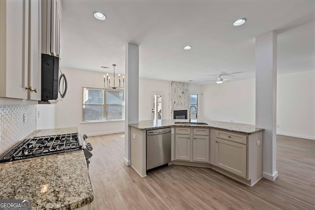 kitchen with sink, decorative backsplash, light wood-type flooring, light stone counters, and stainless steel appliances