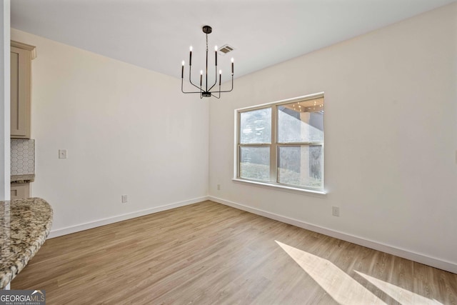 unfurnished dining area with light hardwood / wood-style floors and a notable chandelier