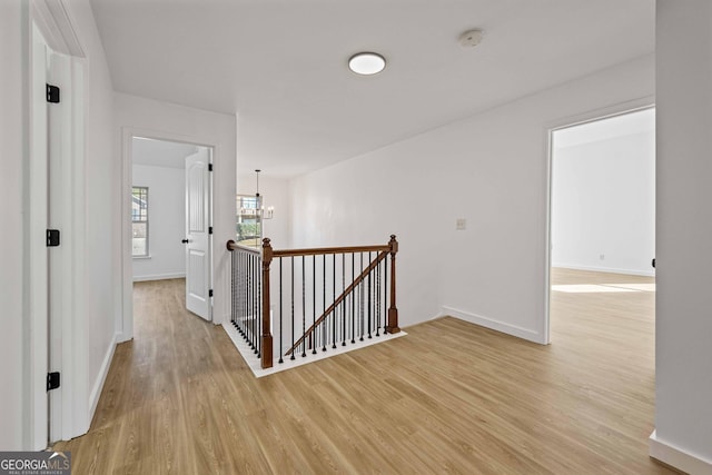 hall with light hardwood / wood-style floors and a notable chandelier