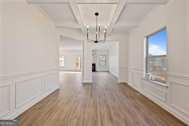 unfurnished dining area with coffered ceiling, crown molding, beam ceiling, light hardwood / wood-style flooring, and a notable chandelier