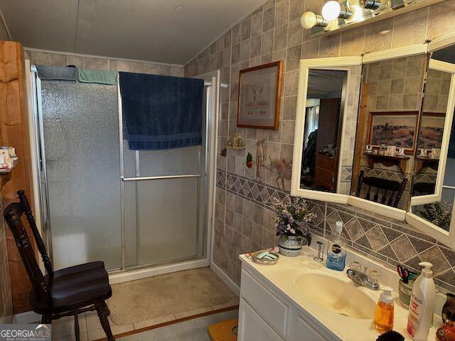 bathroom with vanity, tile walls, lofted ceiling, and a shower with shower door