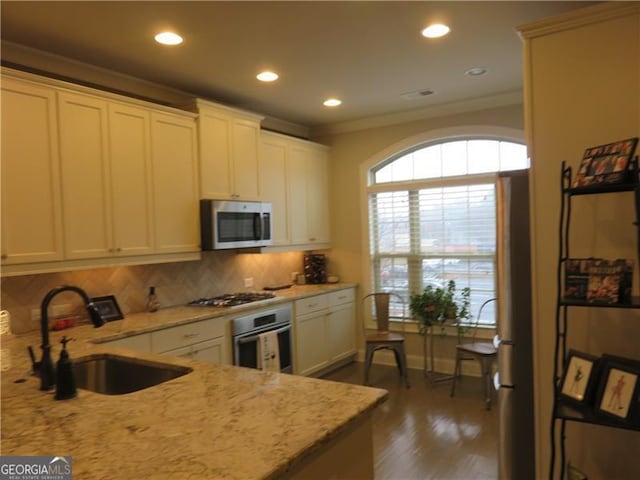 kitchen featuring sink, crown molding, light stone counters, appliances with stainless steel finishes, and dark hardwood / wood-style flooring