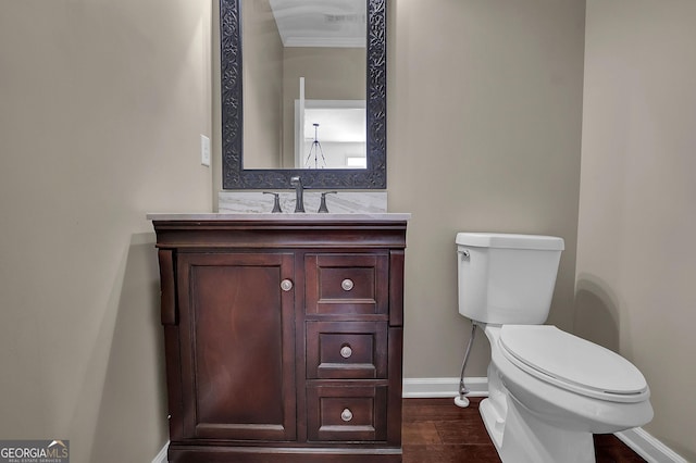 bathroom featuring toilet, vanity, hardwood / wood-style floors, and ornamental molding