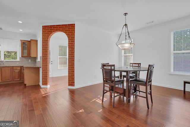 dining room with dark hardwood / wood-style floors, crown molding, and sink