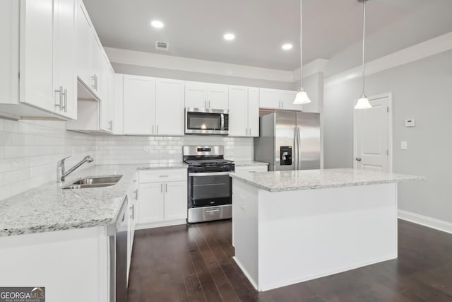 kitchen featuring a kitchen island, appliances with stainless steel finishes, decorative light fixtures, sink, and white cabinets