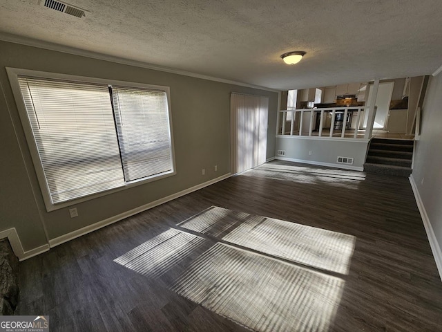 unfurnished living room with dark hardwood / wood-style flooring, ornamental molding, and a textured ceiling