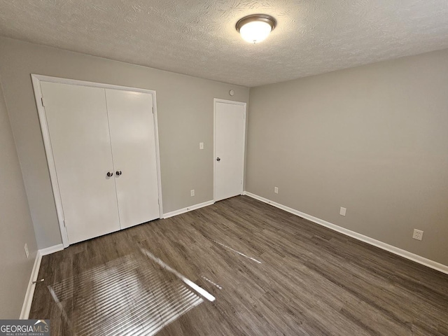 unfurnished bedroom with a closet, dark wood-type flooring, and a textured ceiling