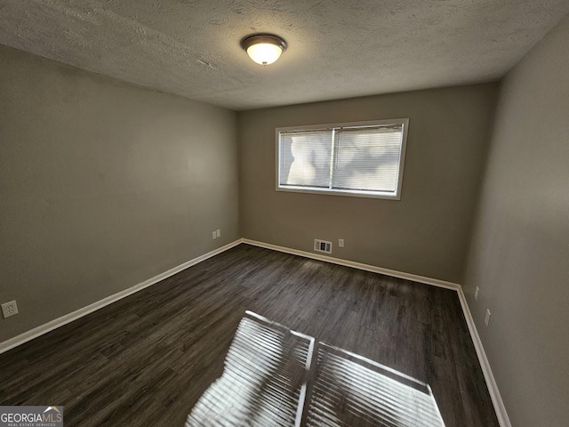 empty room with a textured ceiling and dark hardwood / wood-style floors