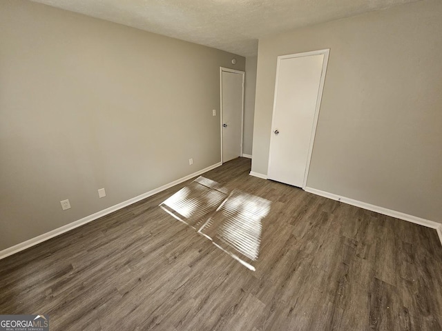 unfurnished bedroom featuring a textured ceiling and dark wood-type flooring