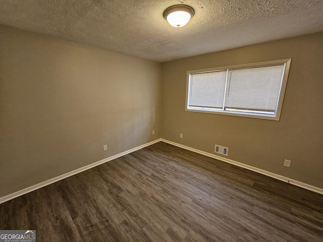 spare room with dark hardwood / wood-style flooring and a textured ceiling