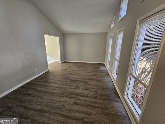 empty room with dark hardwood / wood-style floors and vaulted ceiling