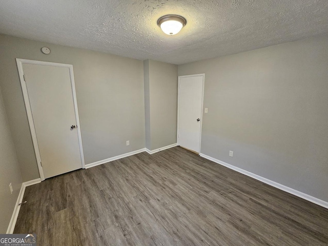 spare room featuring a textured ceiling and dark hardwood / wood-style floors