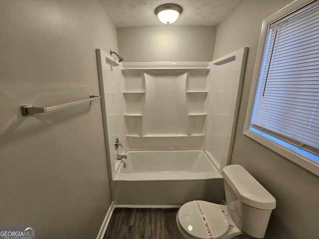 bathroom featuring hardwood / wood-style floors, a textured ceiling, shower / bath combination, and toilet