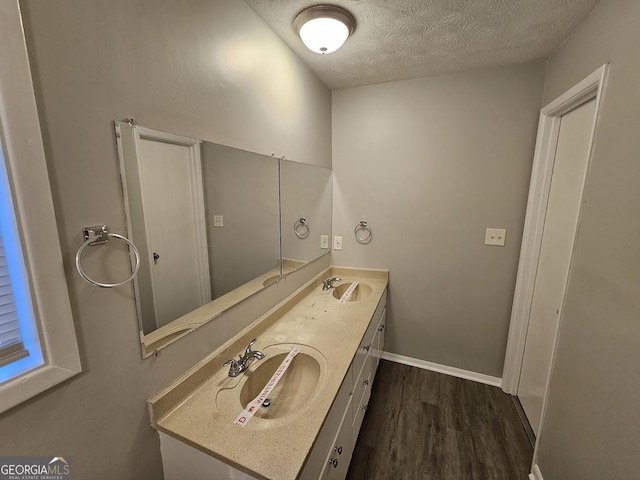 bathroom with hardwood / wood-style floors, vanity, and a textured ceiling