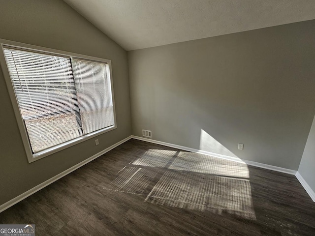 unfurnished room featuring a textured ceiling, dark hardwood / wood-style flooring, and vaulted ceiling