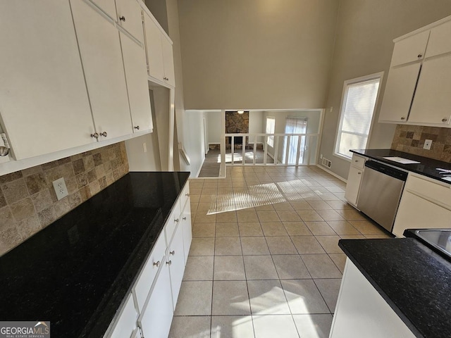 kitchen featuring tasteful backsplash, white cabinetry, light tile patterned flooring, and stainless steel dishwasher