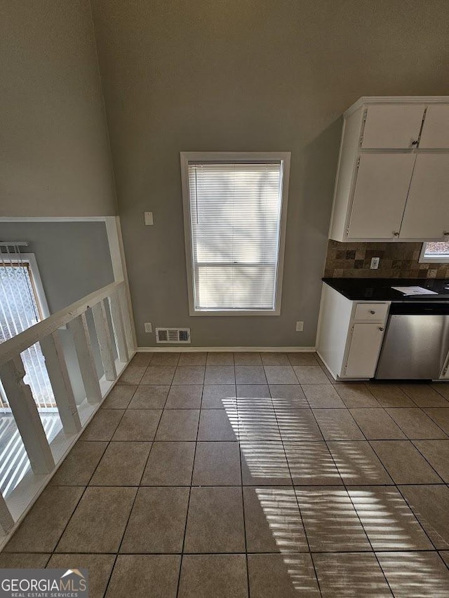 interior space featuring dishwasher, white cabinets, light tile patterned flooring, and plenty of natural light