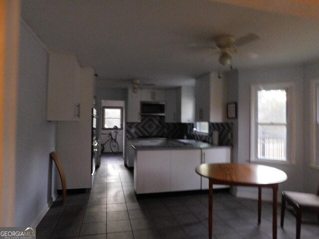 kitchen featuring kitchen peninsula, decorative backsplash, wall oven, ceiling fan, and white cabinetry