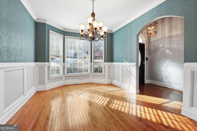 unfurnished dining area featuring ornamental molding, light wood-type flooring, and a notable chandelier