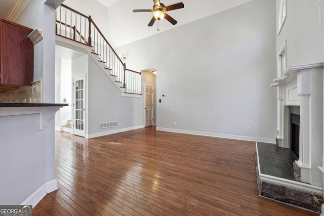 unfurnished living room featuring dark hardwood / wood-style floors, ceiling fan, and a high ceiling