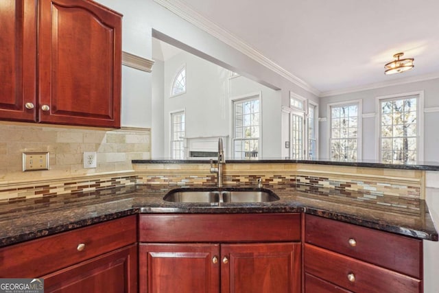 kitchen featuring crown molding, decorative backsplash, sink, and dark stone counters