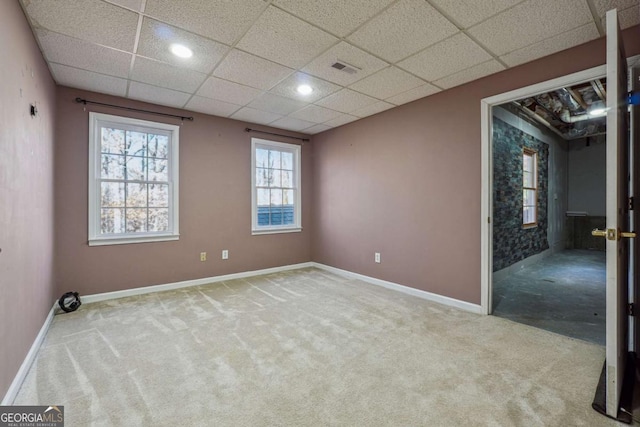 spare room featuring light carpet and a paneled ceiling