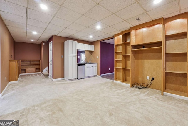 unfurnished living room featuring carpet flooring and a drop ceiling