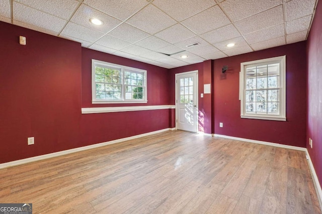 unfurnished room featuring light hardwood / wood-style floors and a drop ceiling