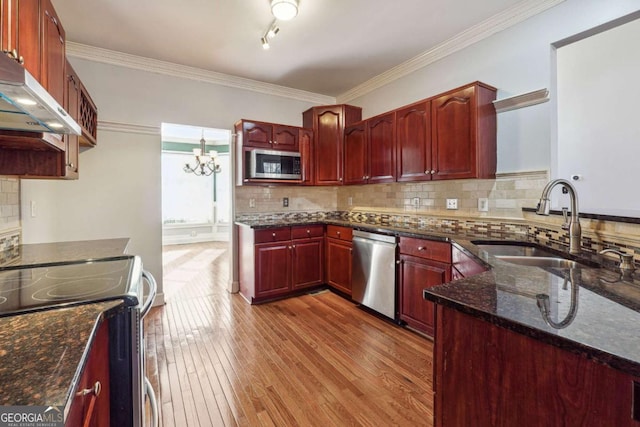 kitchen featuring sink, light hardwood / wood-style flooring, dark stone countertops, appliances with stainless steel finishes, and tasteful backsplash