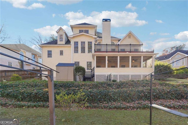 rear view of house with a yard, a sunroom, and a balcony