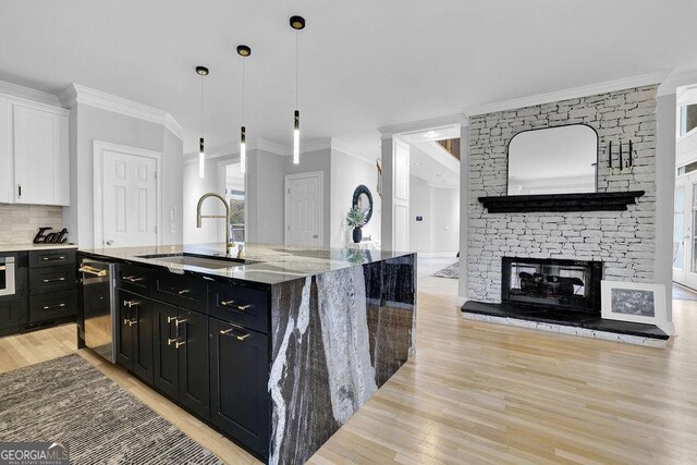 kitchen with pendant lighting, white cabinets, sink, dark stone countertops, and a large island