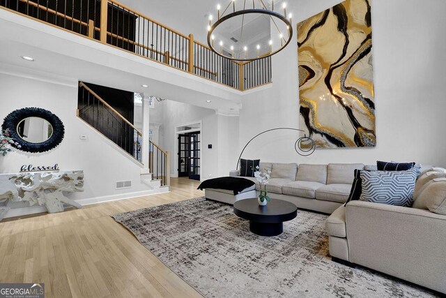 living room with wood-type flooring, a high ceiling, and a notable chandelier