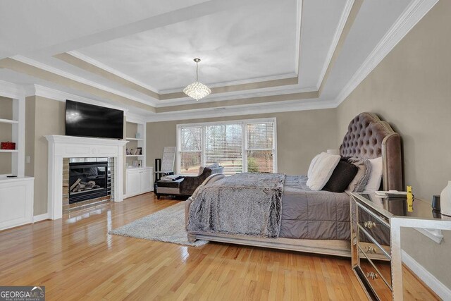 bedroom featuring hardwood / wood-style floors, crown molding, and a tray ceiling