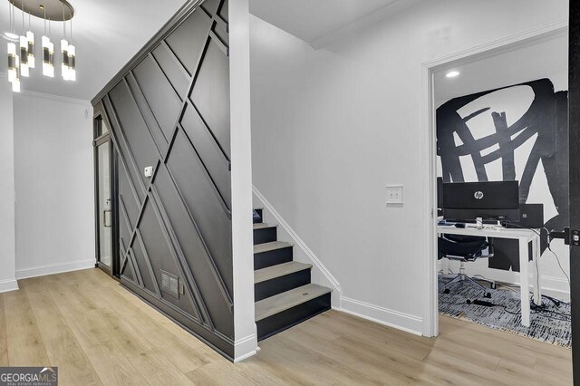 interior space with a chandelier, wood-type flooring, and ornamental molding