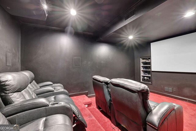 carpeted home theater room with beam ceiling and ornamental molding