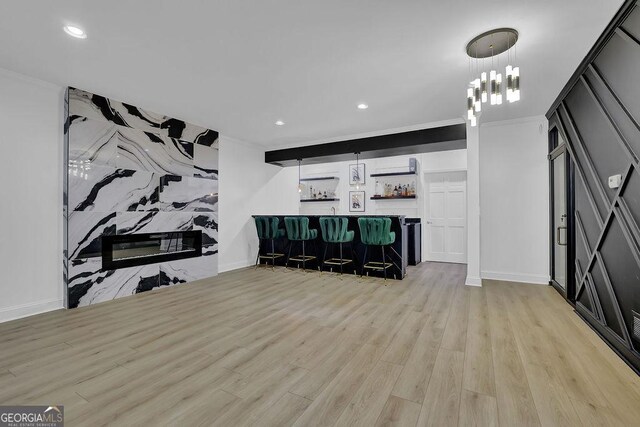 living room with indoor bar, light hardwood / wood-style floors, and ornamental molding