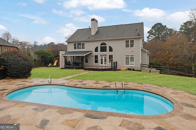 rear view of property featuring a lawn, a pool side deck, and a patio