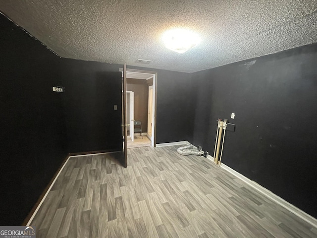 empty room with light hardwood / wood-style floors and a textured ceiling