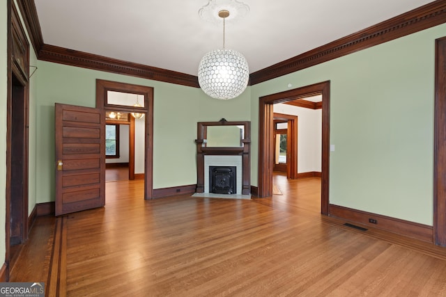 unfurnished living room featuring a chandelier, light wood-type flooring, and ornamental molding