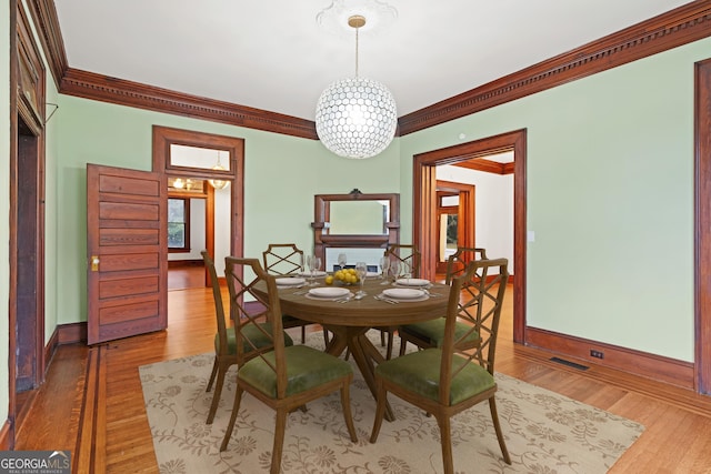 dining space featuring light hardwood / wood-style floors, crown molding, and a chandelier