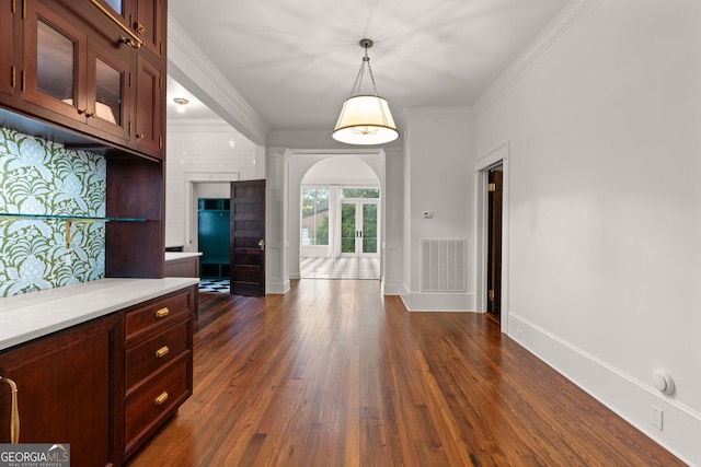 kitchen with decorative light fixtures, crown molding, dark wood-type flooring, and ornate columns