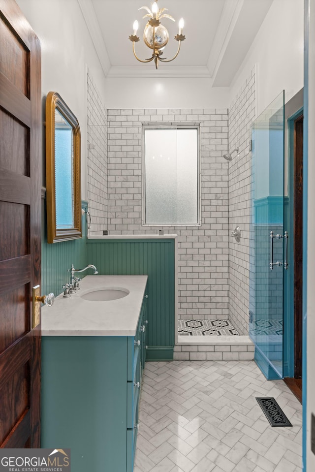 bathroom with tiled shower, crown molding, vanity, and a notable chandelier